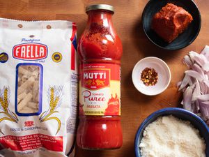 Overhead view of jar of passata, a bag of pasta, and mise en place ingredients.