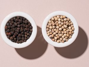 Bowl of black peppercorns and a bowl of white peppercorns