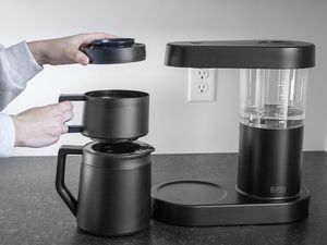 Hands holding the multiple components of the Ratio Six's carafe and brewing system